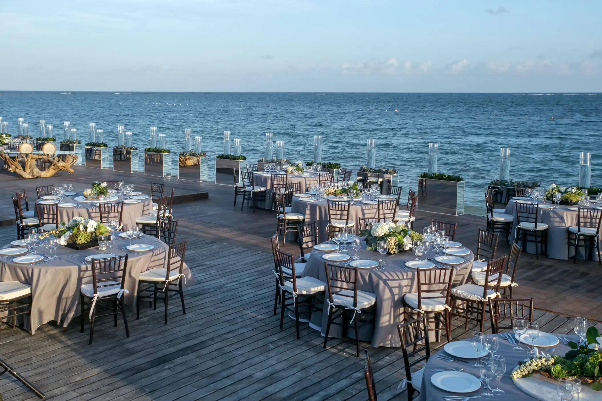 Oceanfront wedding reception with round tables on a wooden deck at Nizuc Resort, Cancun