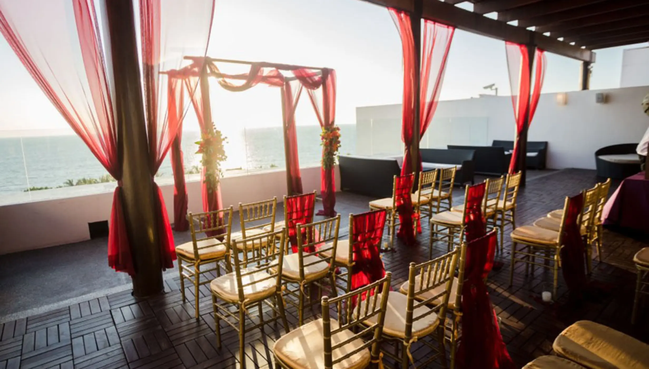 Terrace wedding ceremony with red curtains and gold chairs at Wyndham Alltra Riviera Nayarit, Puerto Vallarta
