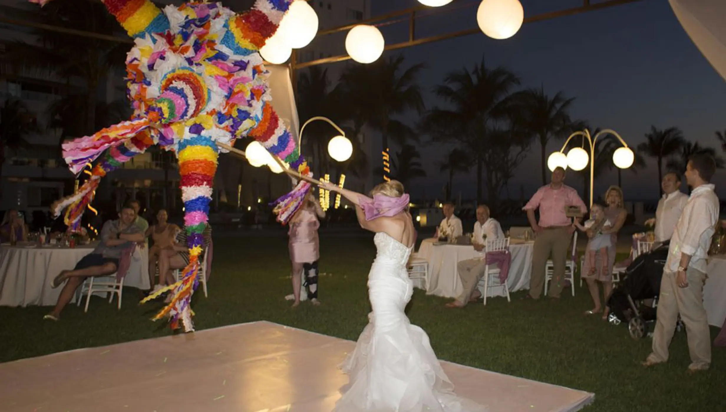 Bride hitting a colorful piñata at a garden wedding reception at Wyndham Alltra Riviera Nayarit, Puerto Vallarta