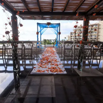 Terrace wedding ceremony with a blue huppah and orange floral aisle at Wyndham Alltra Riviera Nayarit, Puerto Vallarta