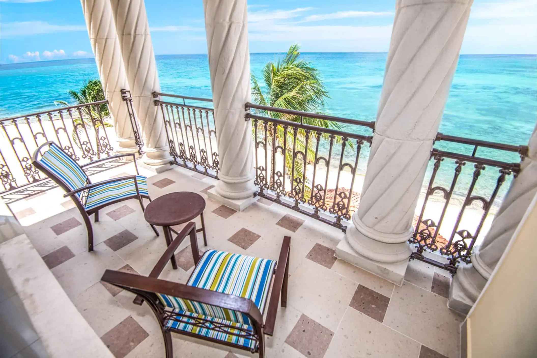 Oceanfront room balcony with spiral columns and blue seating at Wyndham Alltra Playa del Carmen