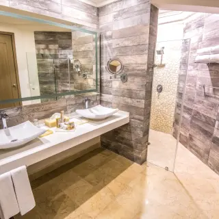 Modern suite bathroom with double vessel sinks and walk-in shower at Wyndham Alltra Playa del Carmen