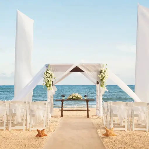 Beachfront wedding ceremony with white huppah and white chairs at Wyndham Alltra Playa del Carmen