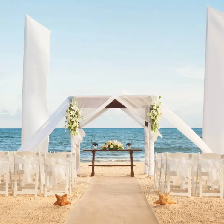 Beachfront wedding ceremony with white huppah and white chairs at Wyndham Alltra Playa del Carmen