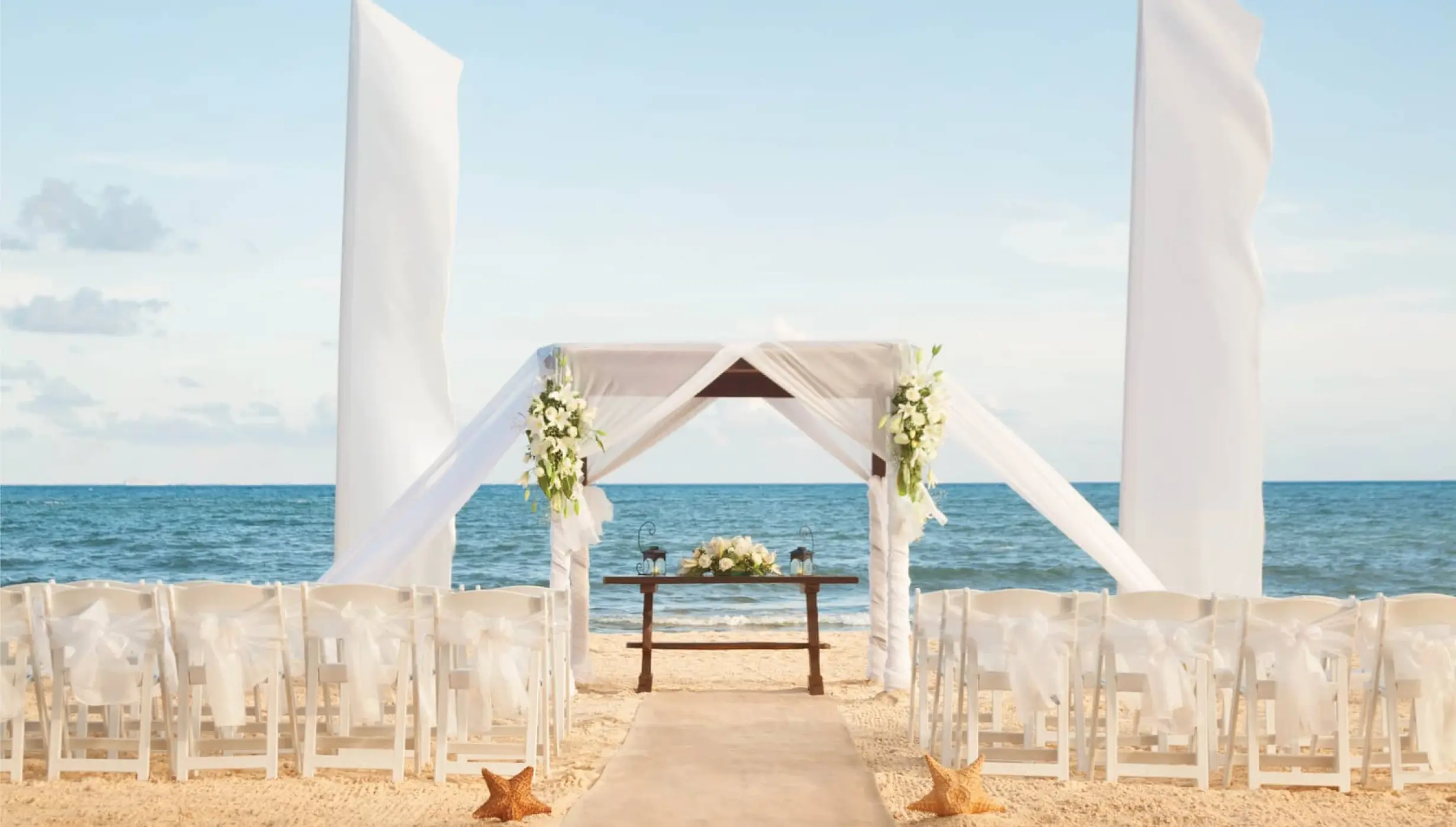 Beachfront wedding ceremony with white huppah and white chairs at Wyndham Alltra Playa del Carmen