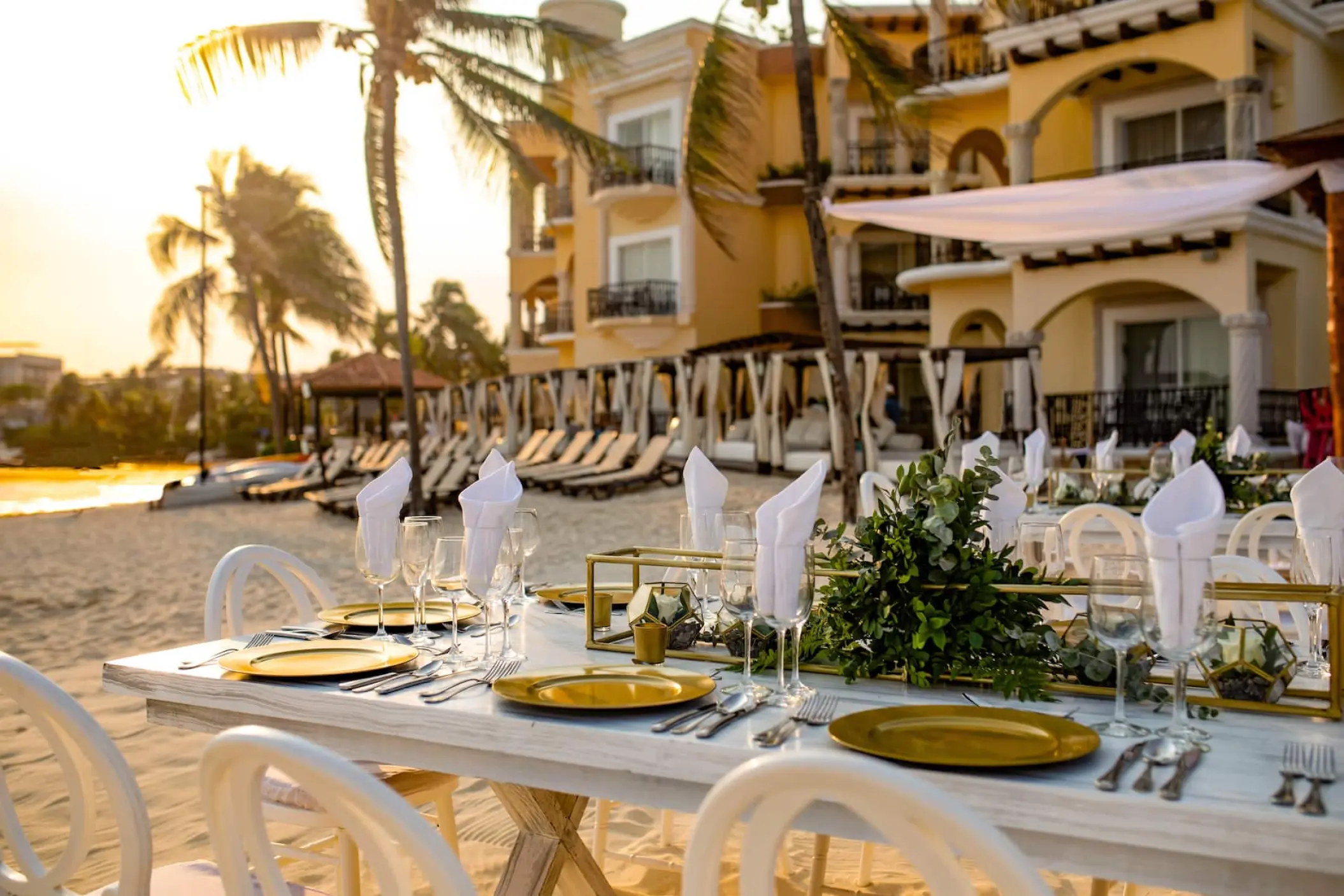 Beachfront wedding reception table with gold plates and greenery at Wyndham Alltra, Playa Del Carmen