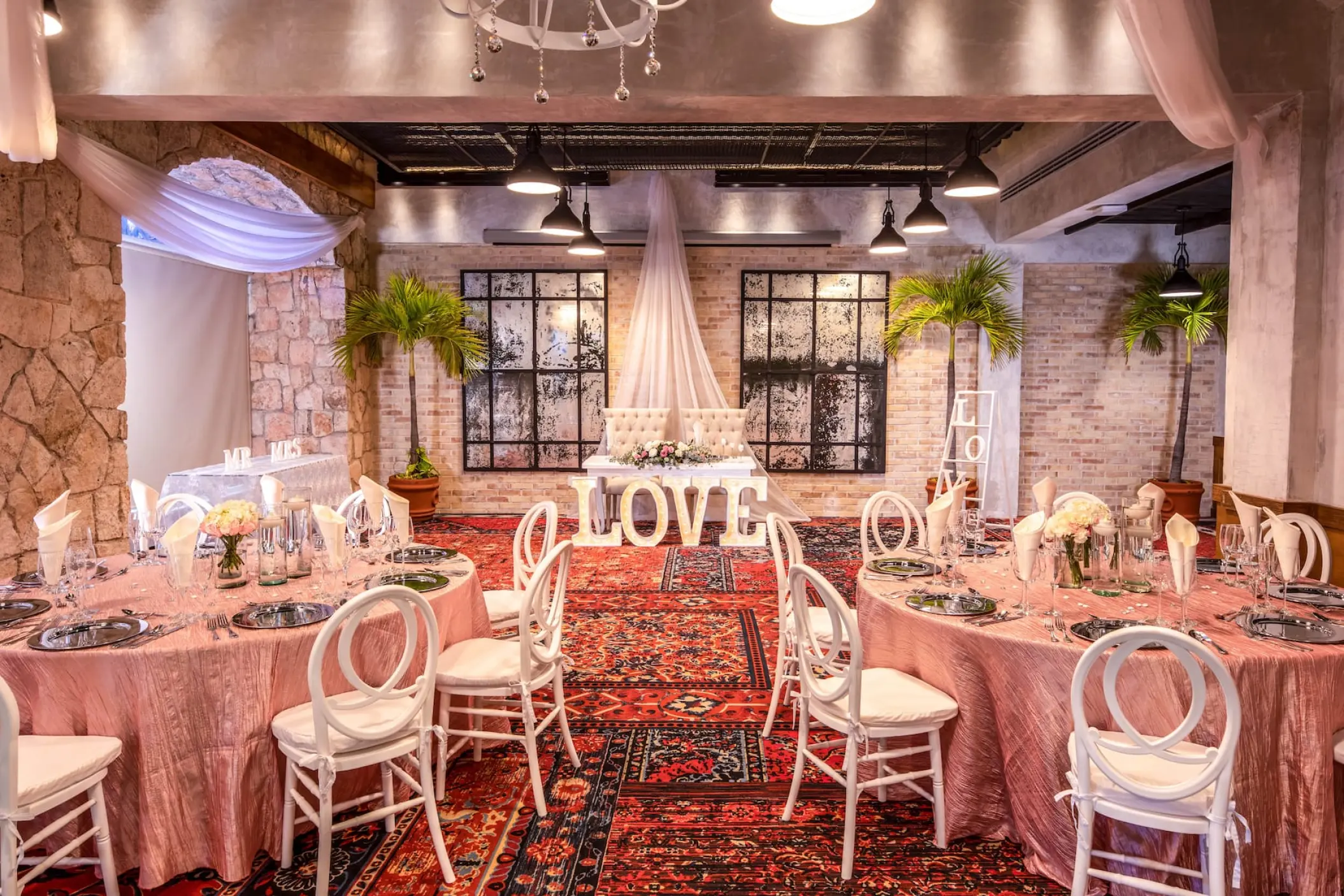 Indoor wedding reception at Wyndham Alltra Playa del Carmen with pink table linens and white LOVE letters