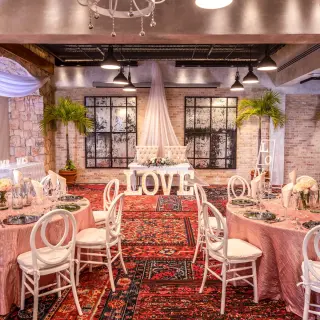 Indoor wedding reception at Wyndham Alltra Playa del Carmen with pink table linens and white LOVE letters