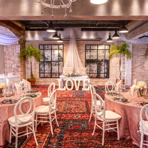 Indoor wedding reception at Wyndham Alltra Playa del Carmen with pink table linens and white LOVE letters