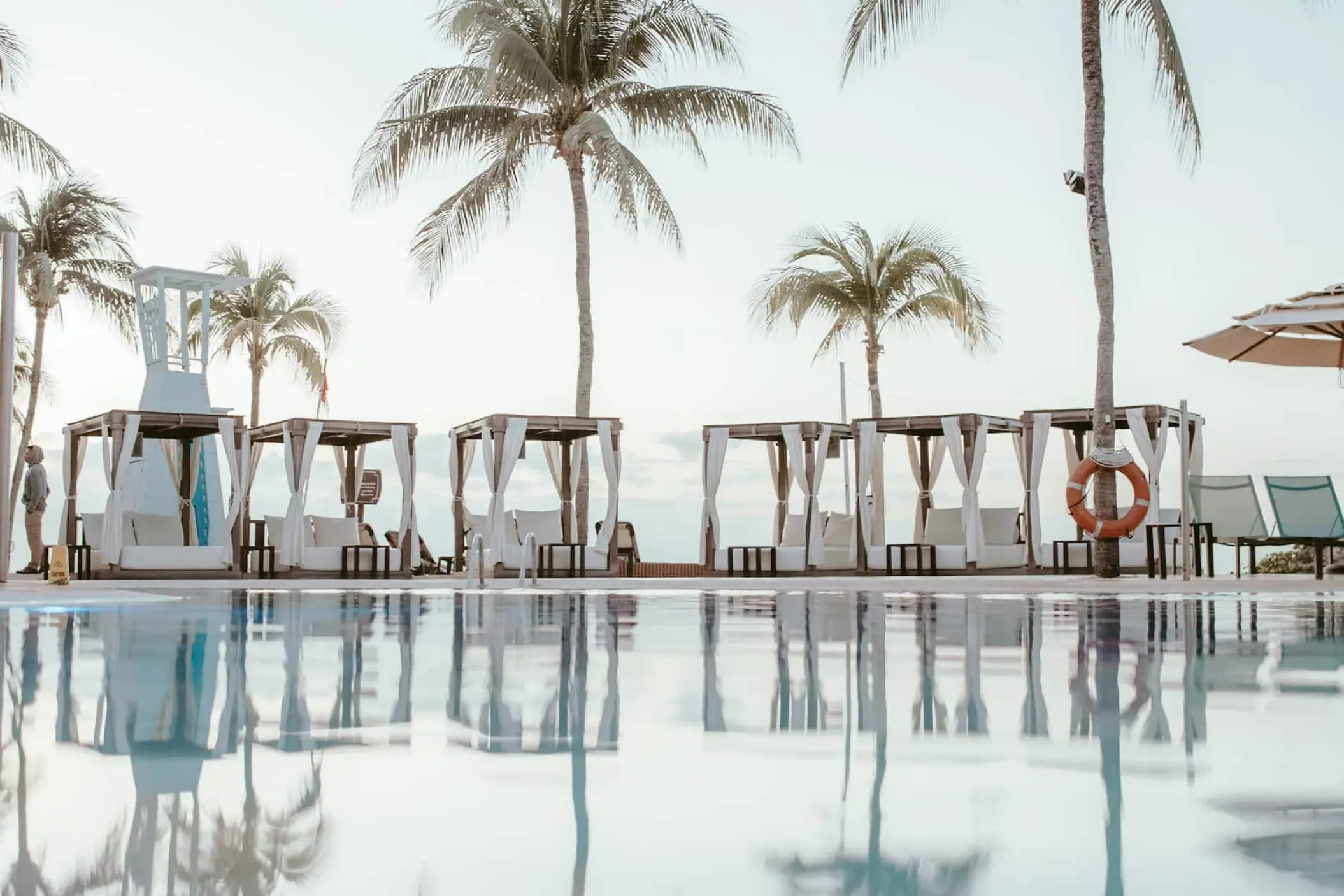 Poolside cabanas reflected in the water at Wyndham Alltra Playa del Carmen
