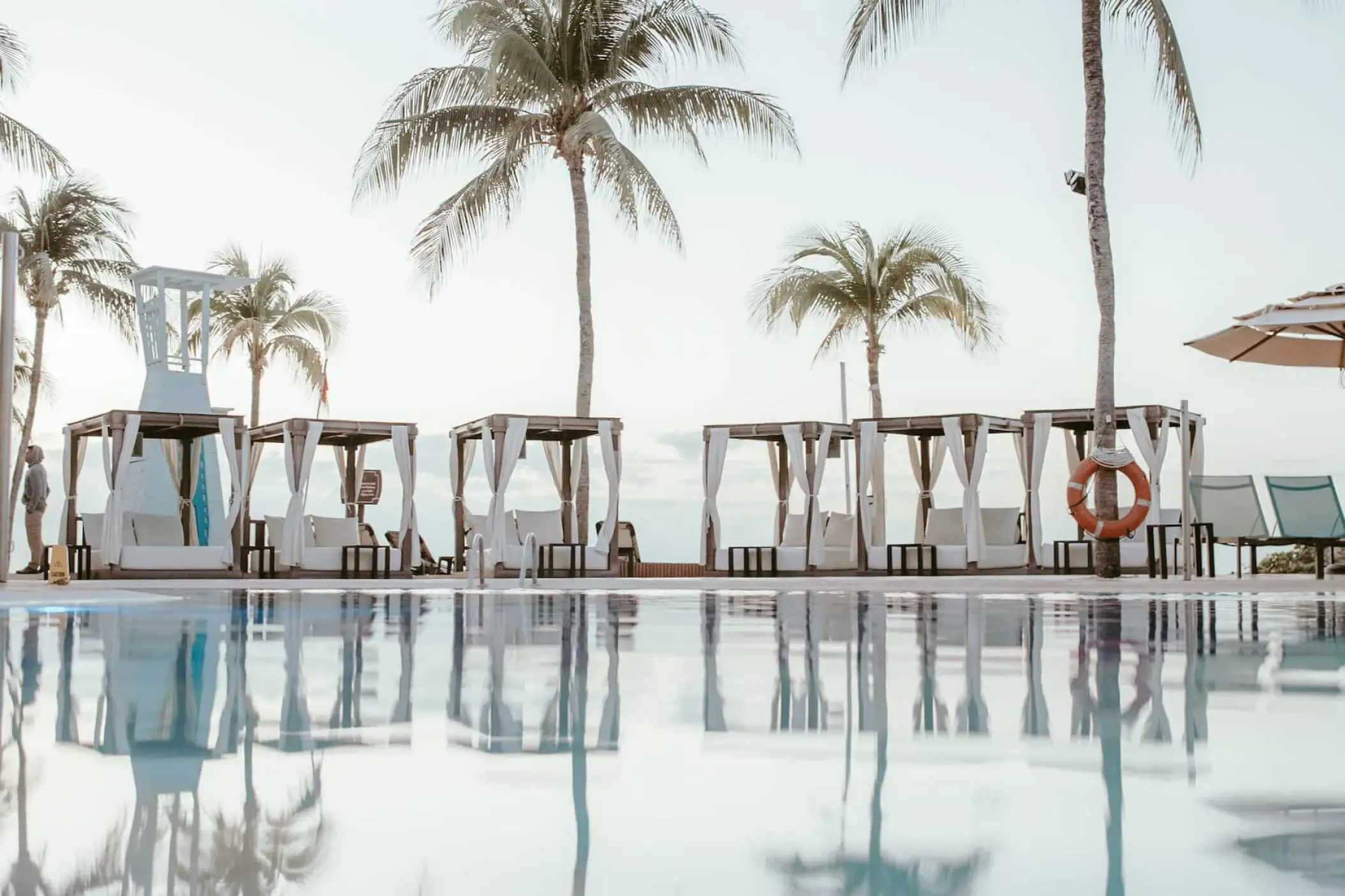 Poolside cabanas reflected in the water at Wyndham Alltra Playa del Carmen