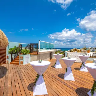 Terrace wedding reception with cocktail tables and a thatched gazebo at Wyndham Alltra Playa del Carmen