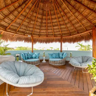 Terrace lounge area under a thatched palapa roof at Wyndham Alltra Playa del Carmen