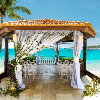 Oceanfront wedding gazebo with white chairs and drapes at Wyndham Alltra Playa del Carmen