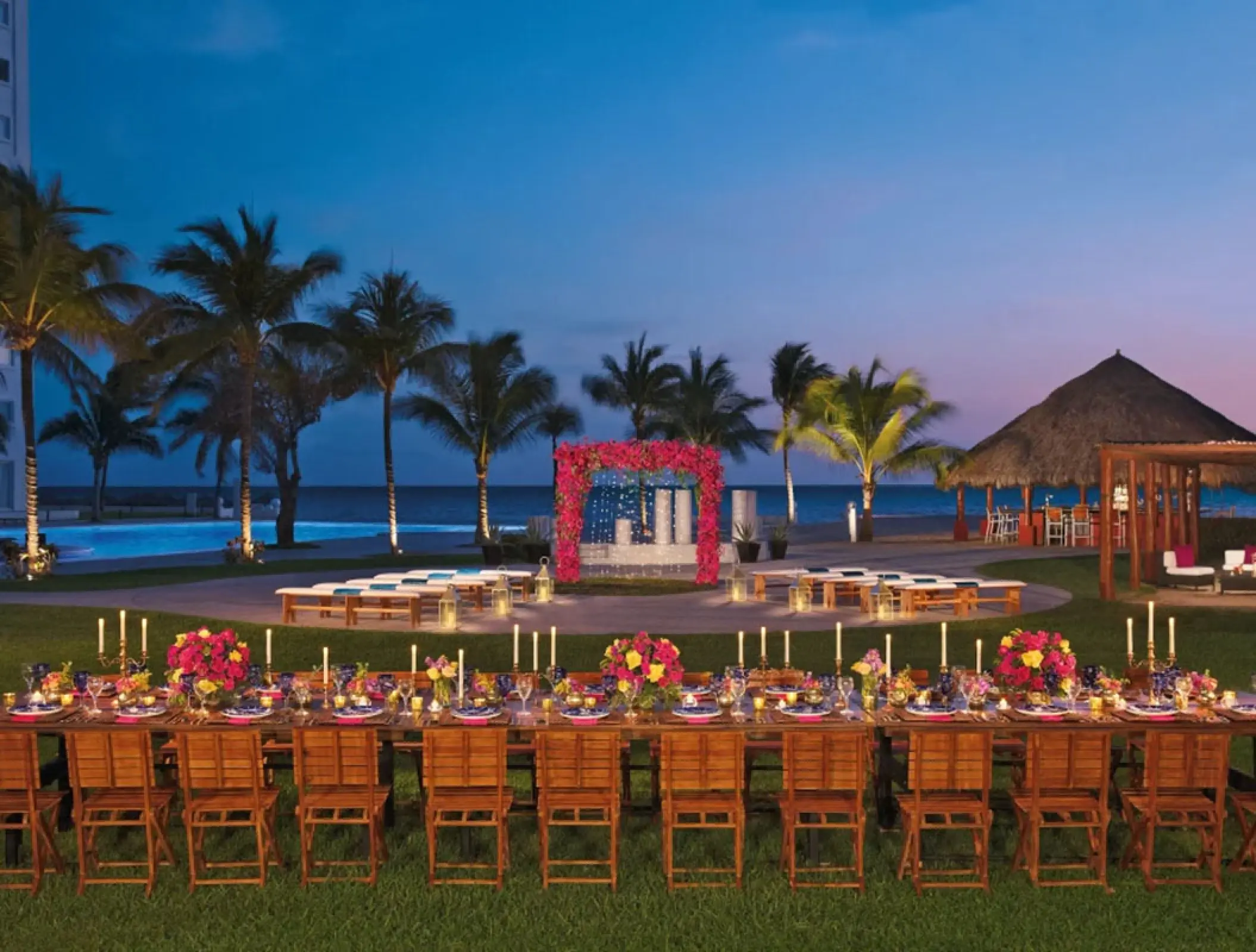 Outdoor wedding reception and ceremony setup with pink floral arch at Wyndham Alltra Riviera Nayarit, Puerto Vallarta