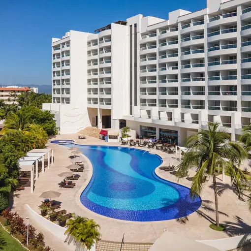 Curved swimming pool and white multistory buildings at Wyndham Alltra Riviera Nayarit, Puerto Vallarta