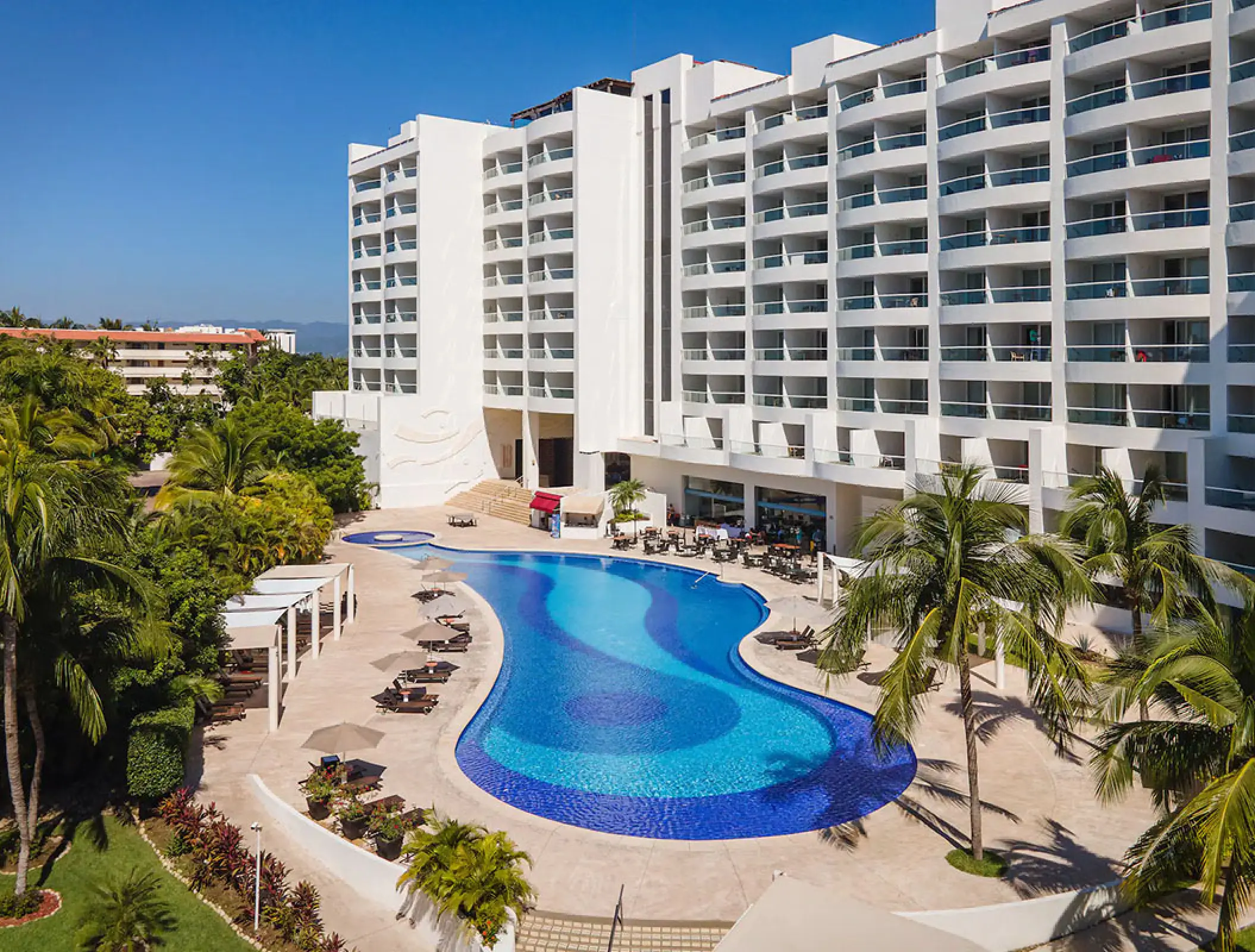 Curved swimming pool and white multistory buildings at Wyndham Alltra Riviera Nayarit, Puerto Vallarta