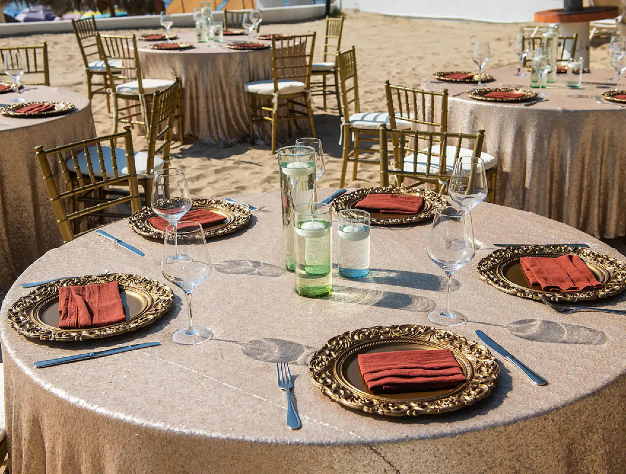 Wedding reception tables with gold linens and gold chairs on the beach at Wyndham Alltra Riviera Nayarit, Puerto Vallarta