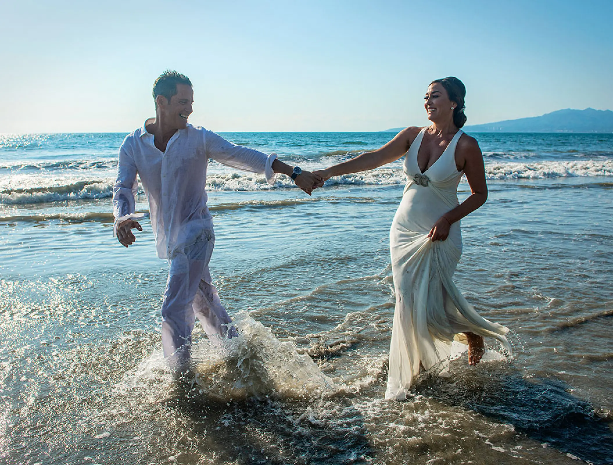 Bride and groom running through waves at Wyndham Alltra Riviera Nayarit, Puerto Vallarta