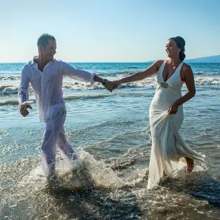 Bride and groom running through waves at Wyndham Alltra Riviera Nayarit, Puerto Vallarta