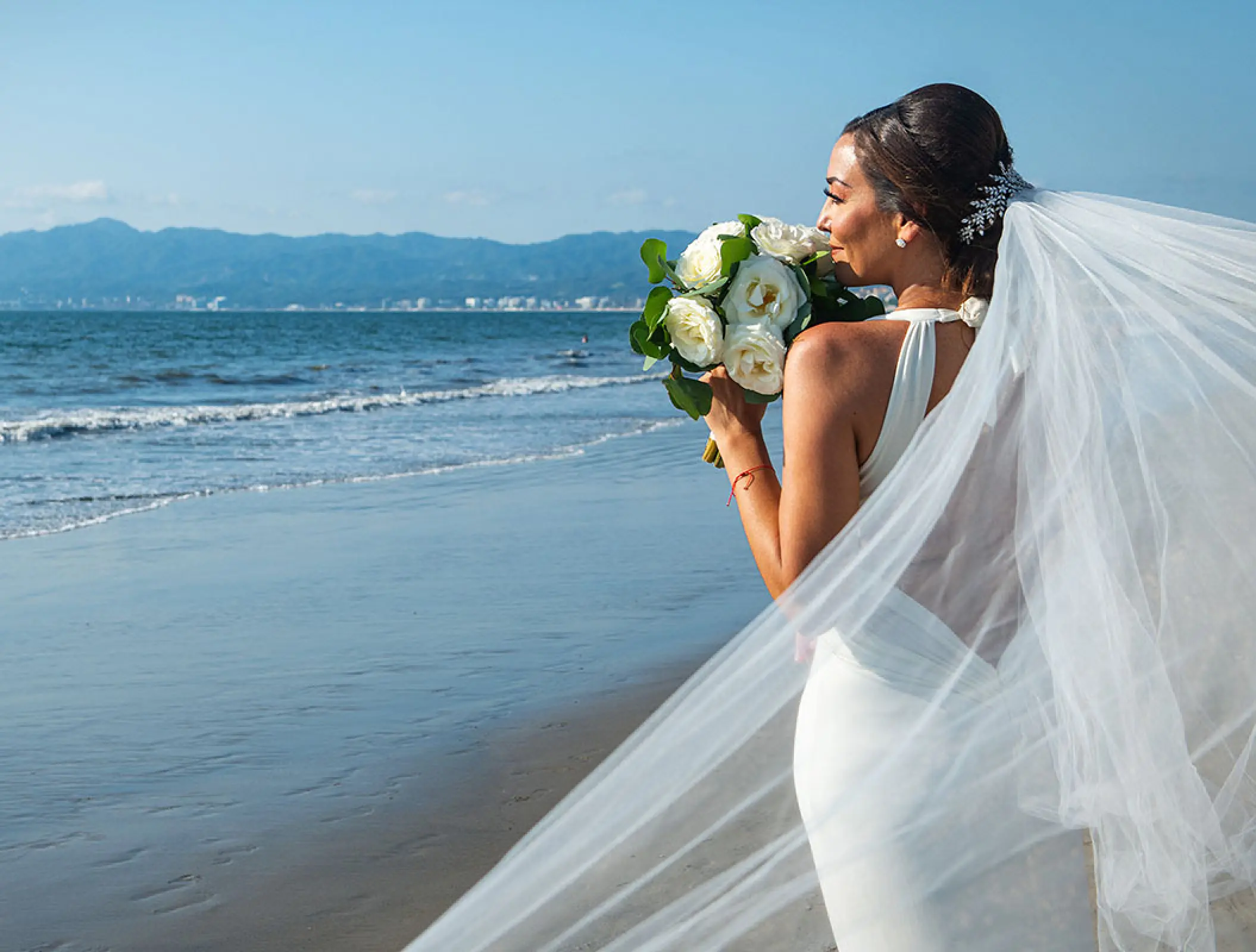 Bride holding a white rose bouquet on the beach at Wyndham Alltra Riviera Nayarit, Puerto Vallarta
