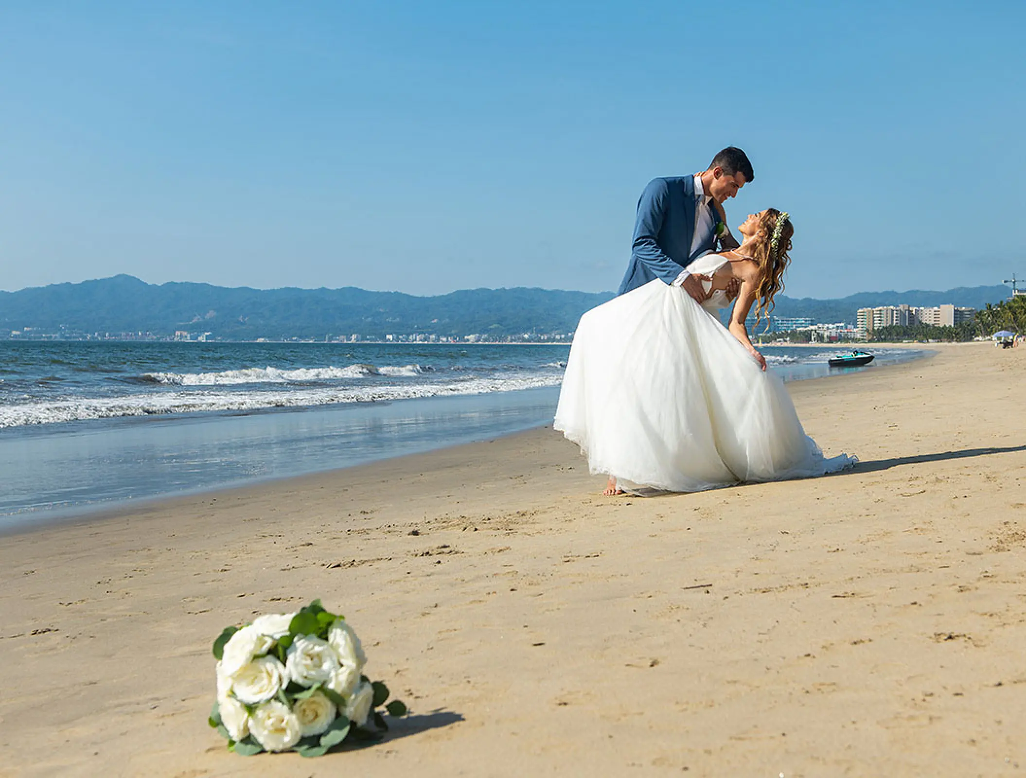 Groom dipping his bride on the beach at Wyndham Alltra Riviera Nayarit, Puerto Vallarta