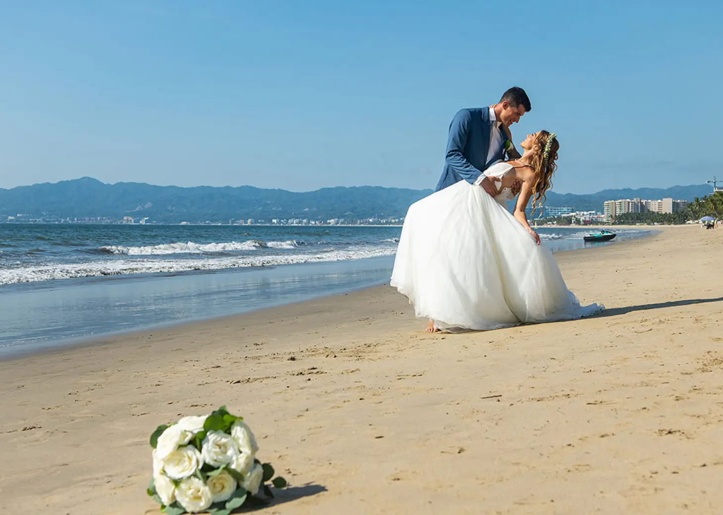 Groom dipping his bride on the beach at Wyndham Alltra Riviera Nayarit, Puerto Vallarta