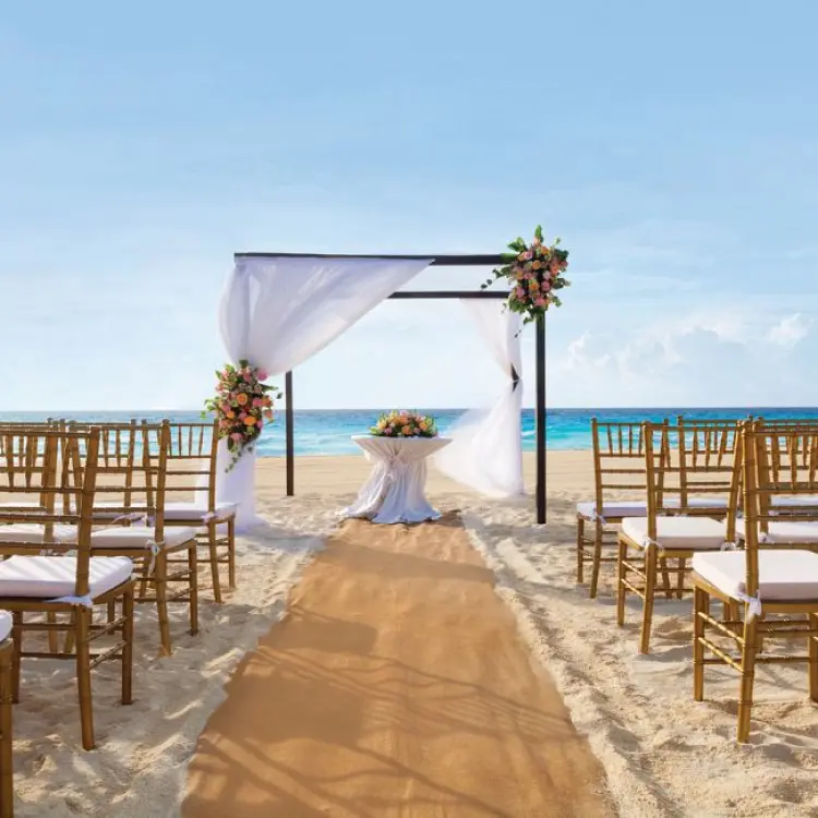 Beachfront wedding ceremony setup with bamboo chairs and draped huppah at Sunscape Cancun, Cancun