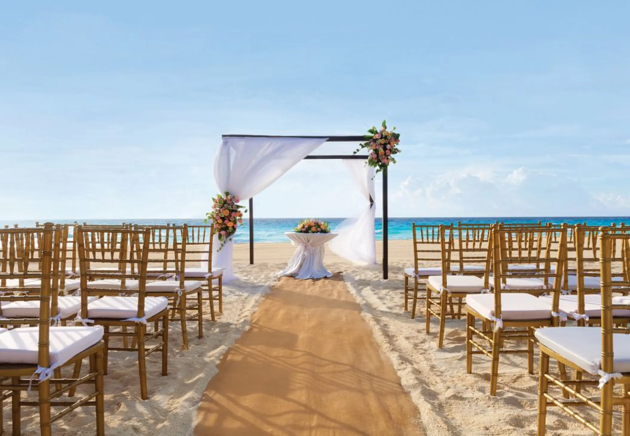 Beachfront wedding ceremony setup with bamboo chairs and draped huppah at Sunscape Cancun, Cancun