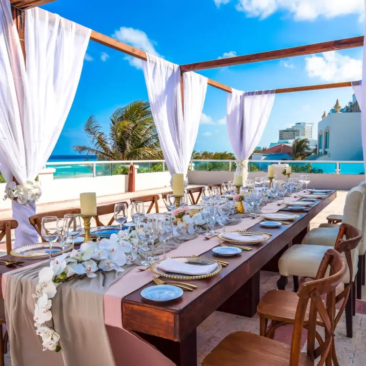 Oceanfront wedding reception table under a draped pergola at Sunscape Cancun