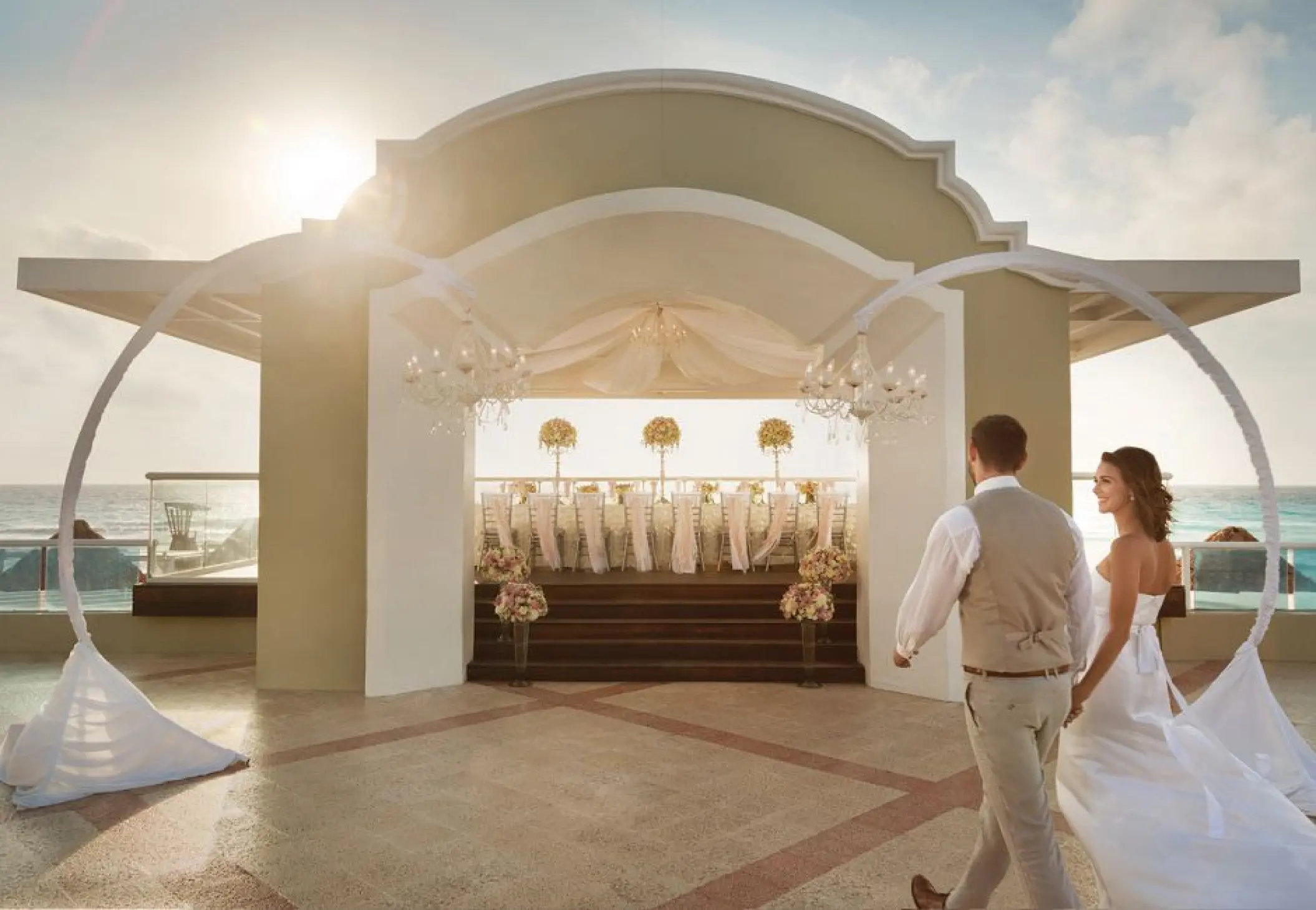 The bride and groom walking toward a terrace wedding reception at Sunscape Cancun, Cancun