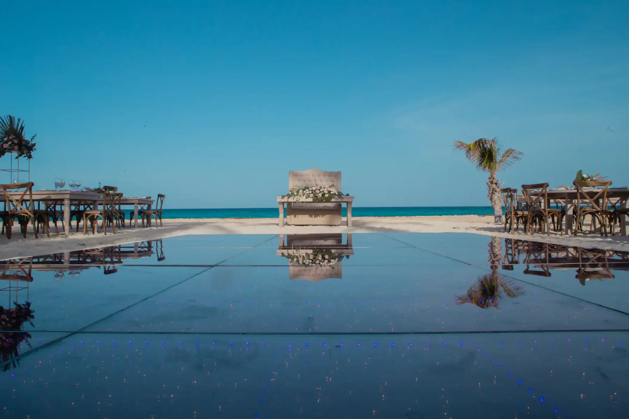 Beachfront wedding reception setup with dance floor and wooden tables at Sunscape Cancun
