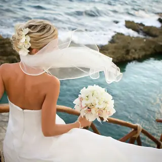 Bride with a white bouquet overlooking the ocean at Hotel Xcaret Mexico, Riviera Maya