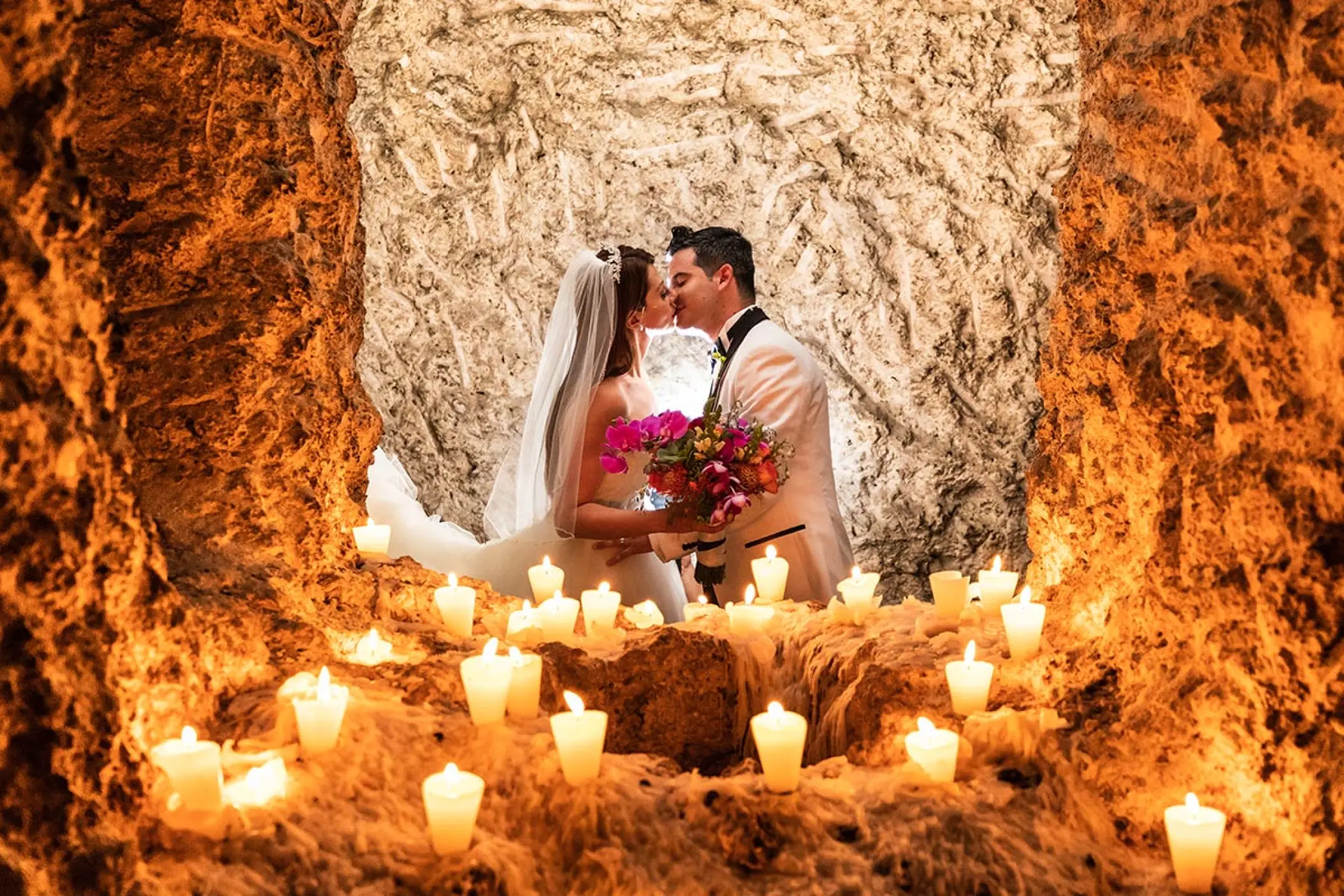 The bride and groom kissing in a candlelit cave at Hotel Xcaret Mexico, Riviera Maya
