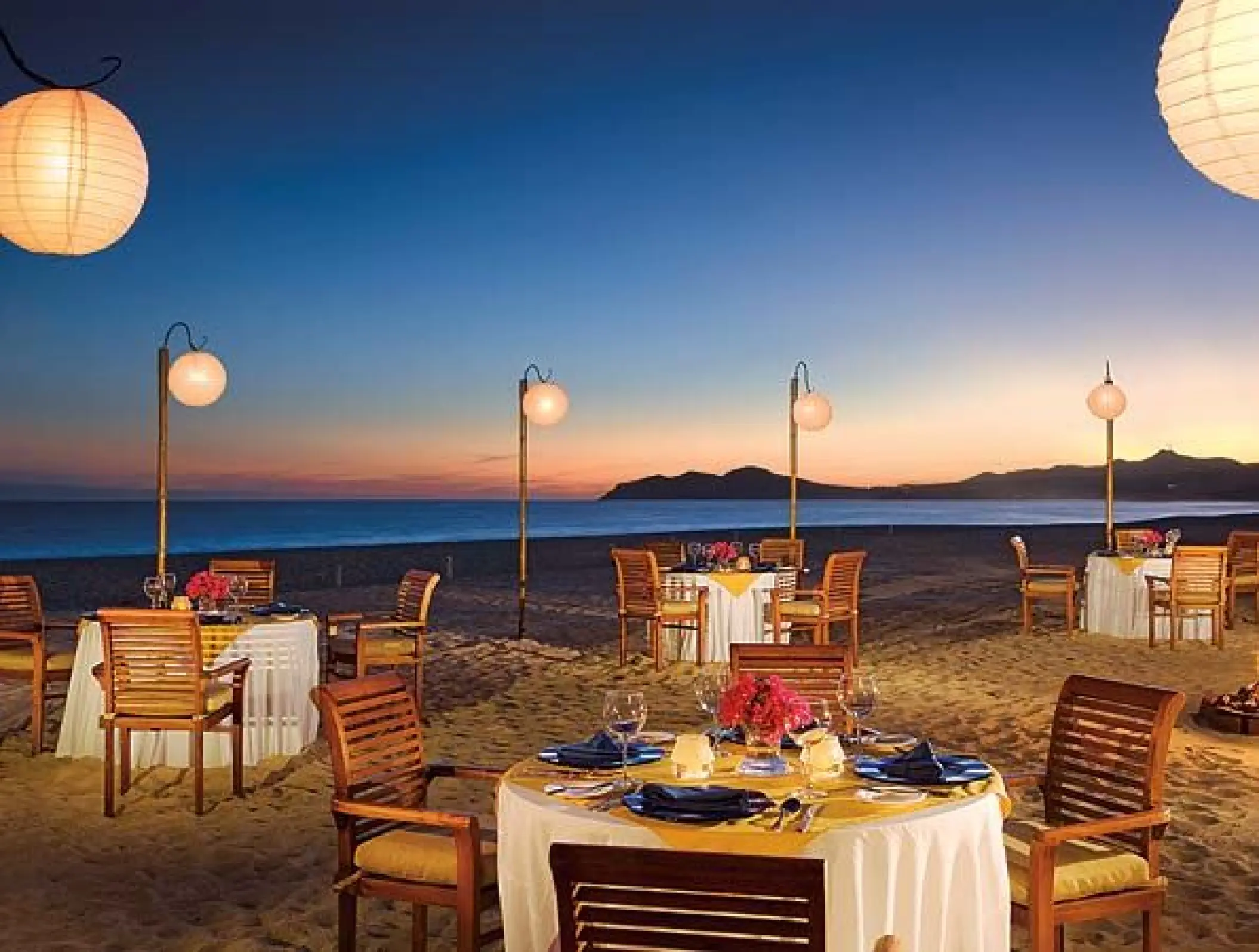 Sunset beach reception with paper lanterns and white-clothed tables at Zoetry Casa del Mar, Cabo San Lucas