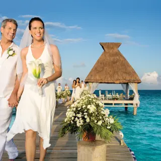 The bride and groom walking down an ocean pier at Zoetry Paraiso de la Bonita, Riviera Maya