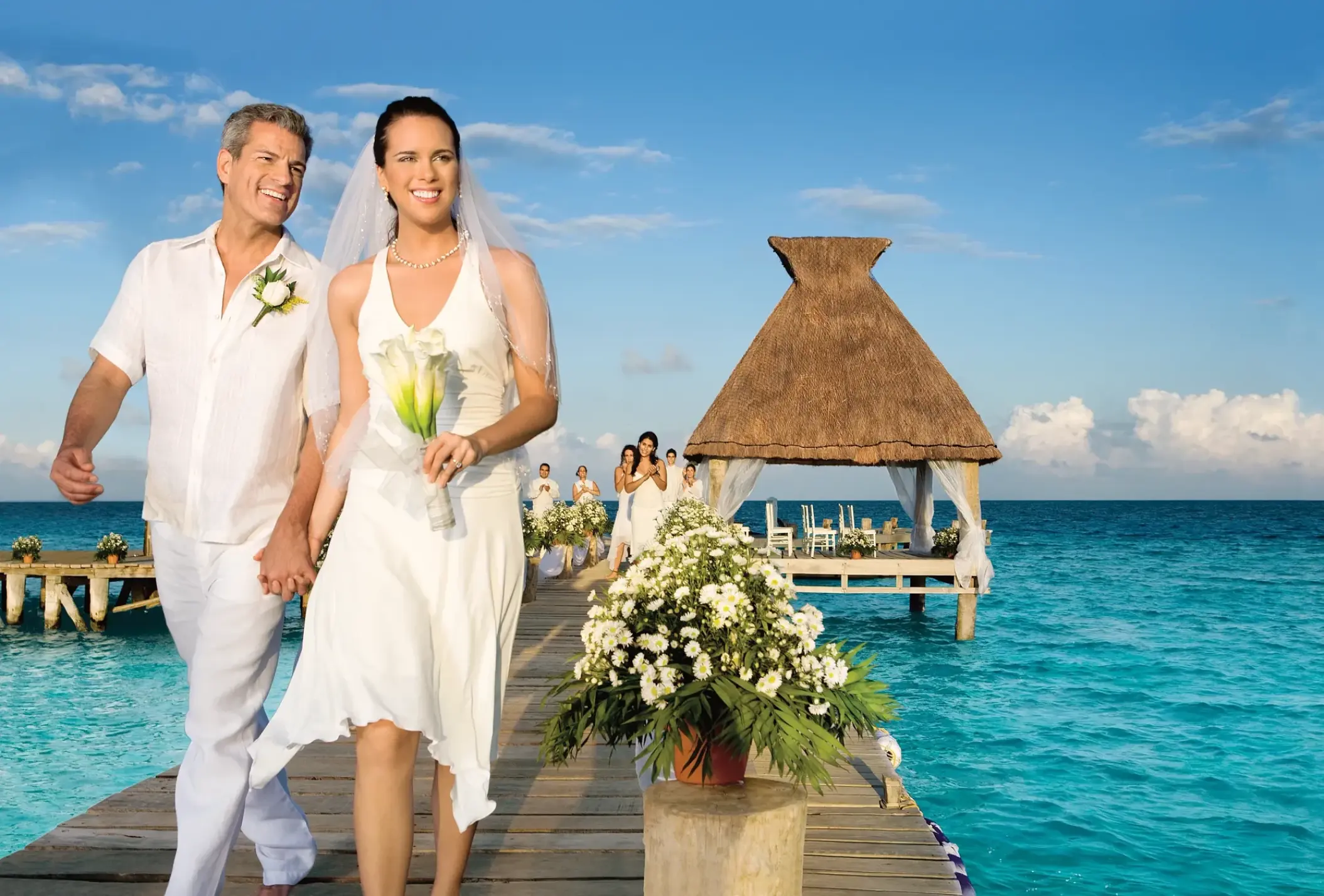The bride and groom walking down an ocean pier at Zoetry Paraiso de la Bonita, Riviera Maya
