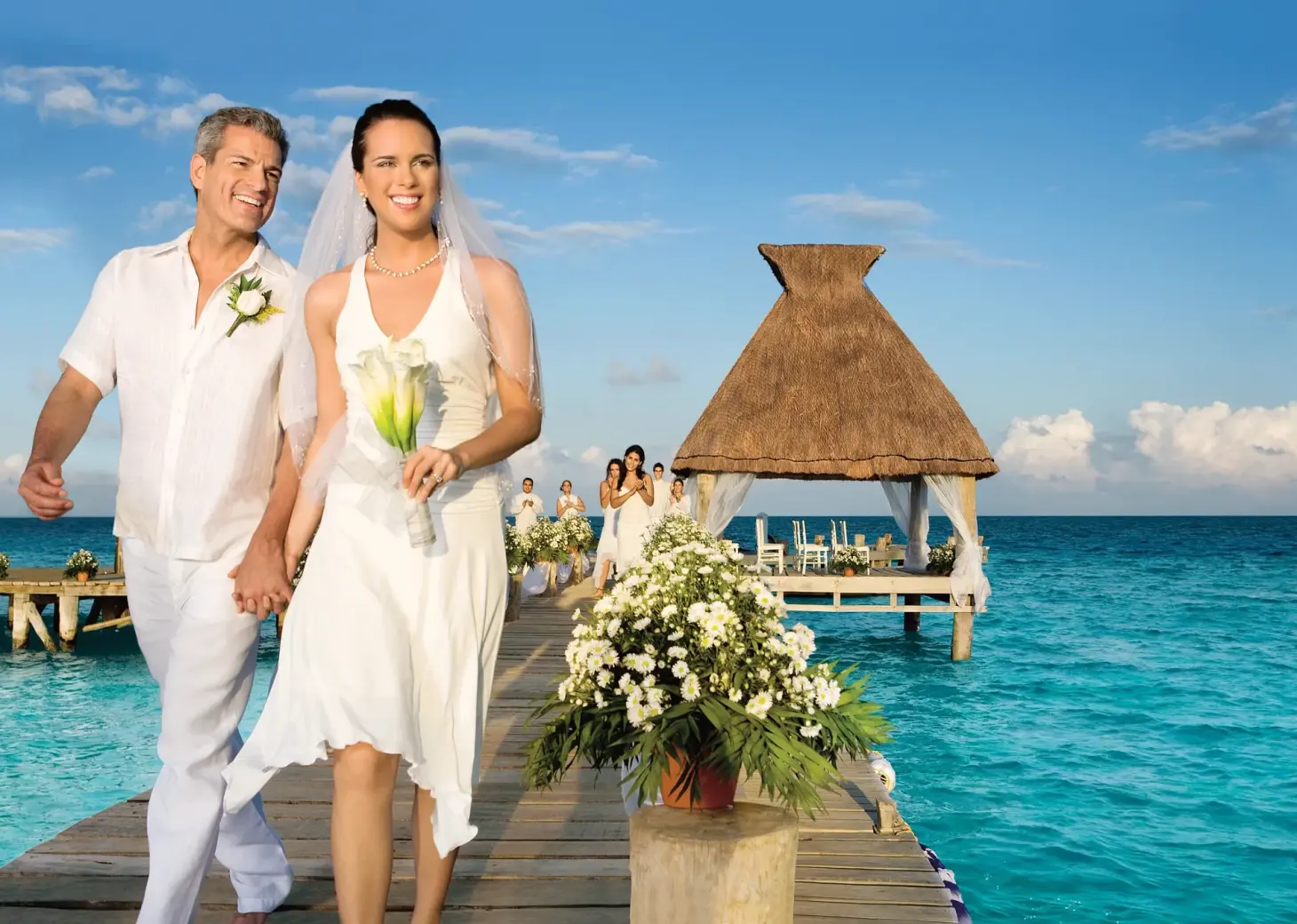 The bride and groom walking down an ocean pier at Zoetry Paraiso de la Bonita, Riviera Maya