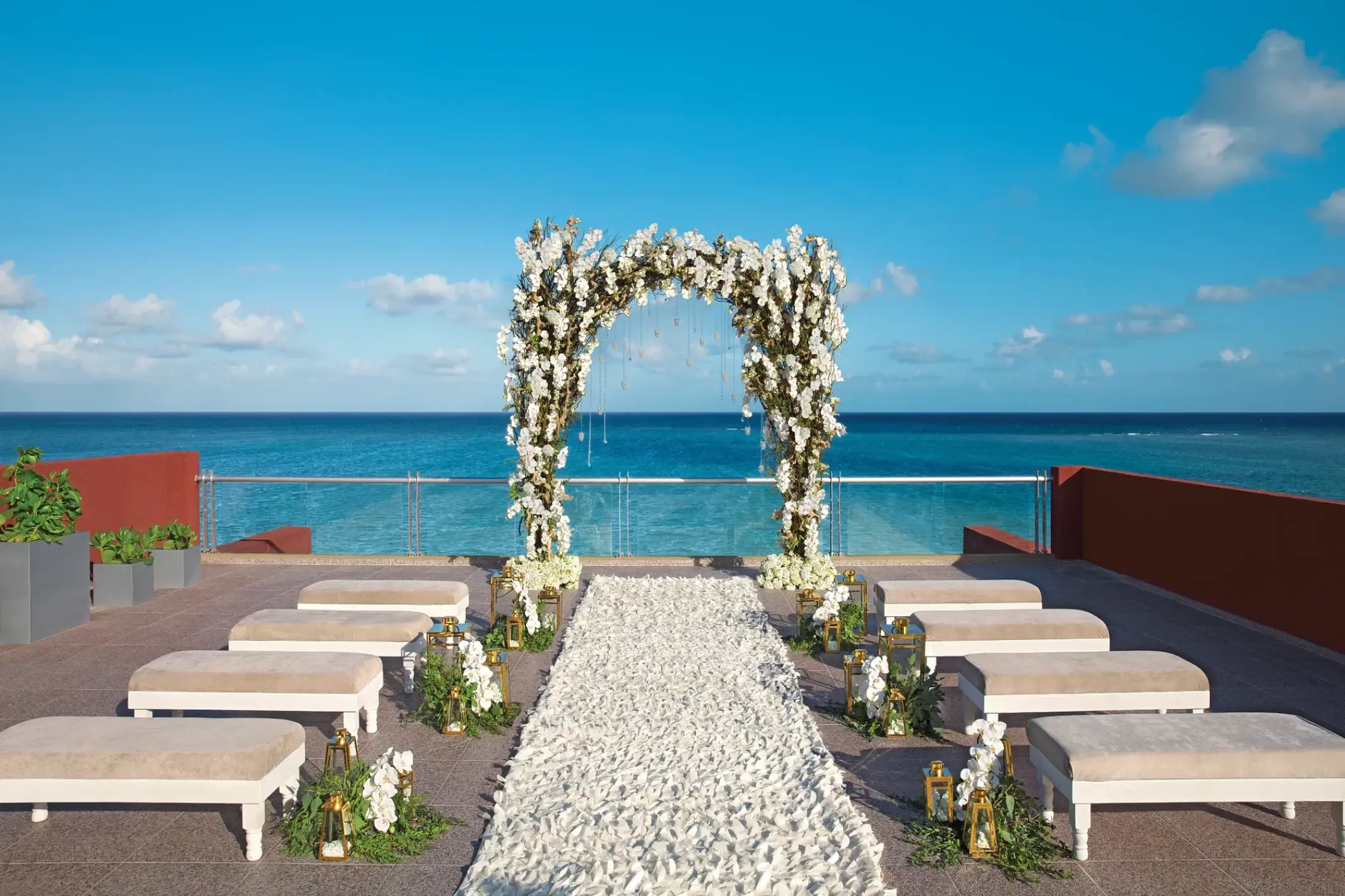 Rooftop wedding ceremony setup with white floral arch and ocean views at Zoetry Paraiso de la Bonita, Riviera Maya
