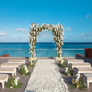 Rooftop wedding ceremony setup with white floral arch and ocean views at Zoetry Paraiso de la Bonita, Riviera Maya