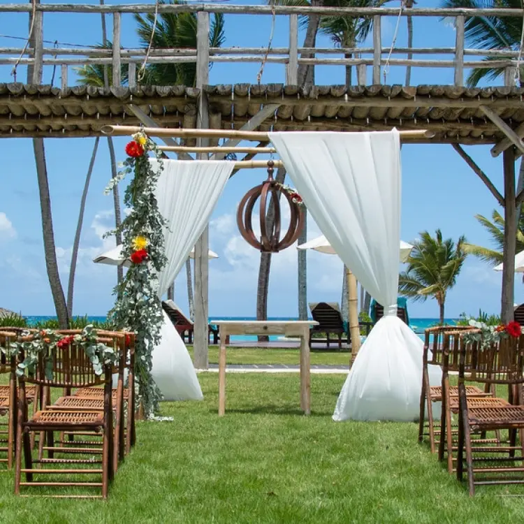 Garden wedding ceremony setup with wooden chairs and white fabric arch at Zoetry Agua, Punta Cana