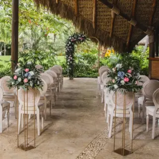 Sheltered terrace wedding ceremony with floral stands and round-back chairs at Zoetry Agua, Punta Cana