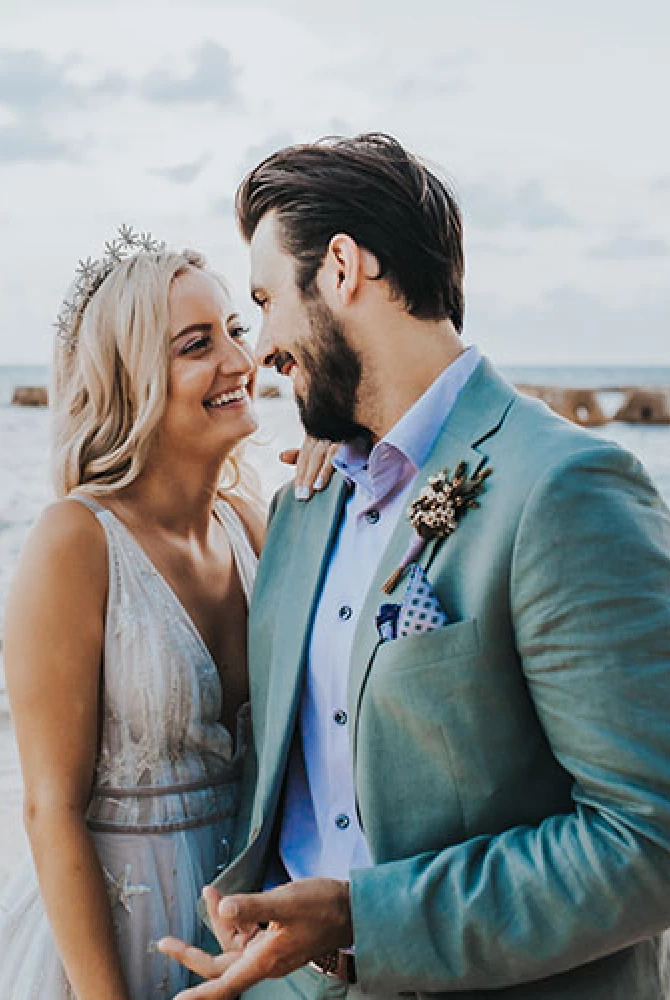 Newlyweds smiling to each other on the beach