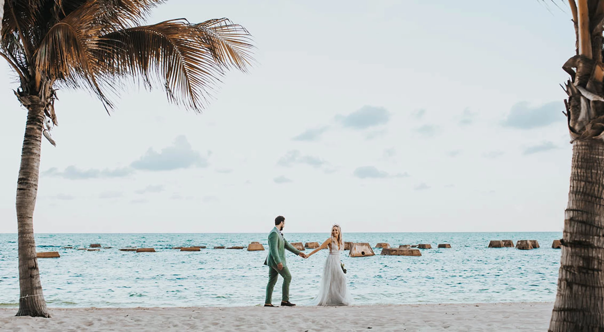 Wide shot of newlyweds walking on the beach