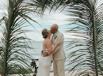 Gorm and bride's first kiss underneath a beatiful palmtree made arch