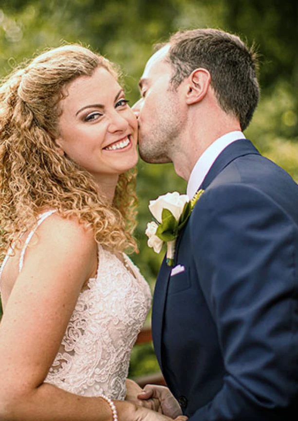 Bride smiles when groom kisses her chick
