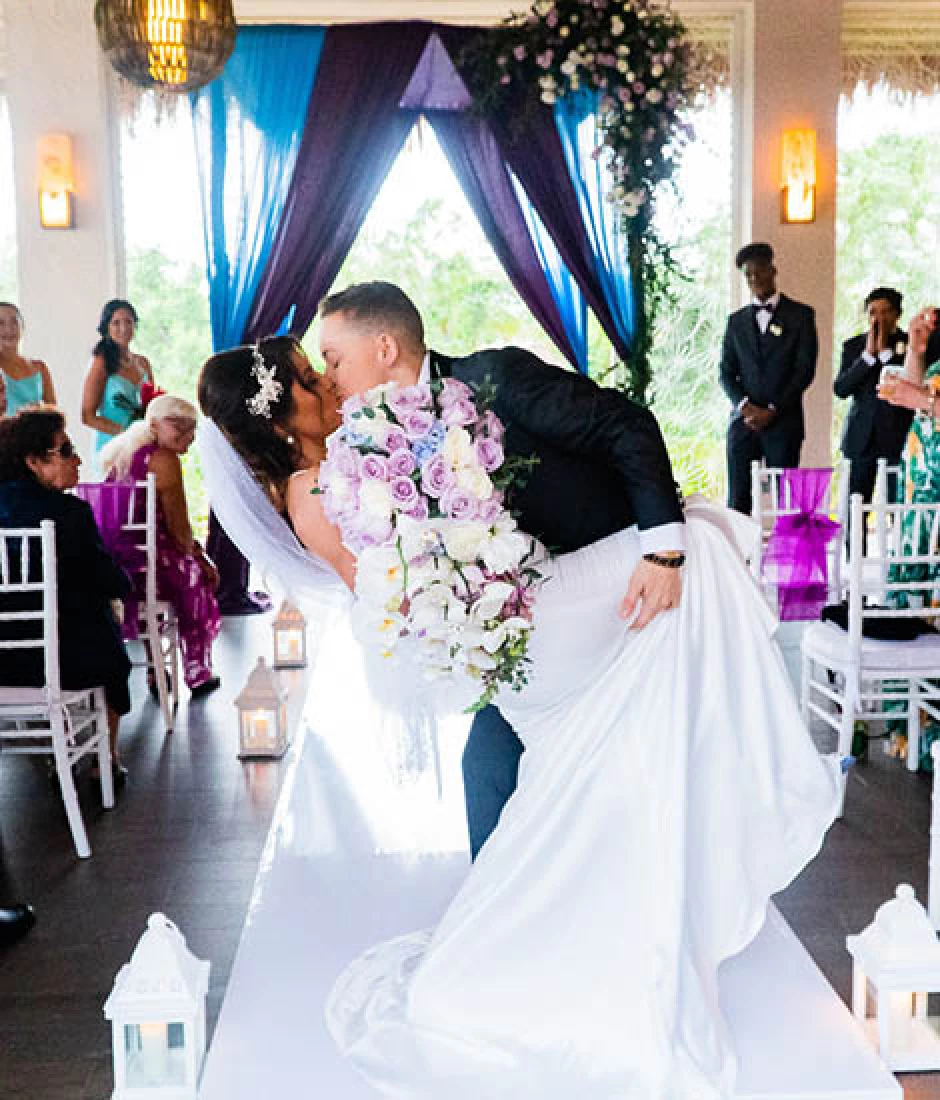 newlyweds kisses on front of the isle