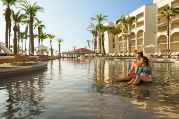 Couple on the main pool at Dreams Los Cabos Suites Golf Resort & Spa