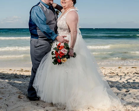 Groom and bride pose for a shot on the beach
