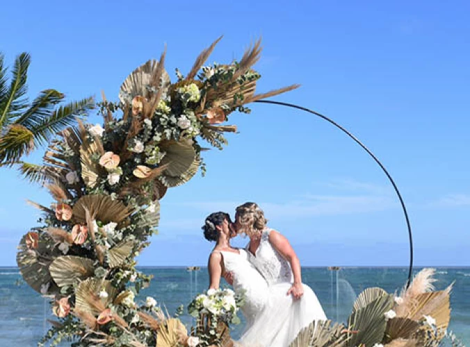 two newlywed brides kiss on a beautiful isle on the beach